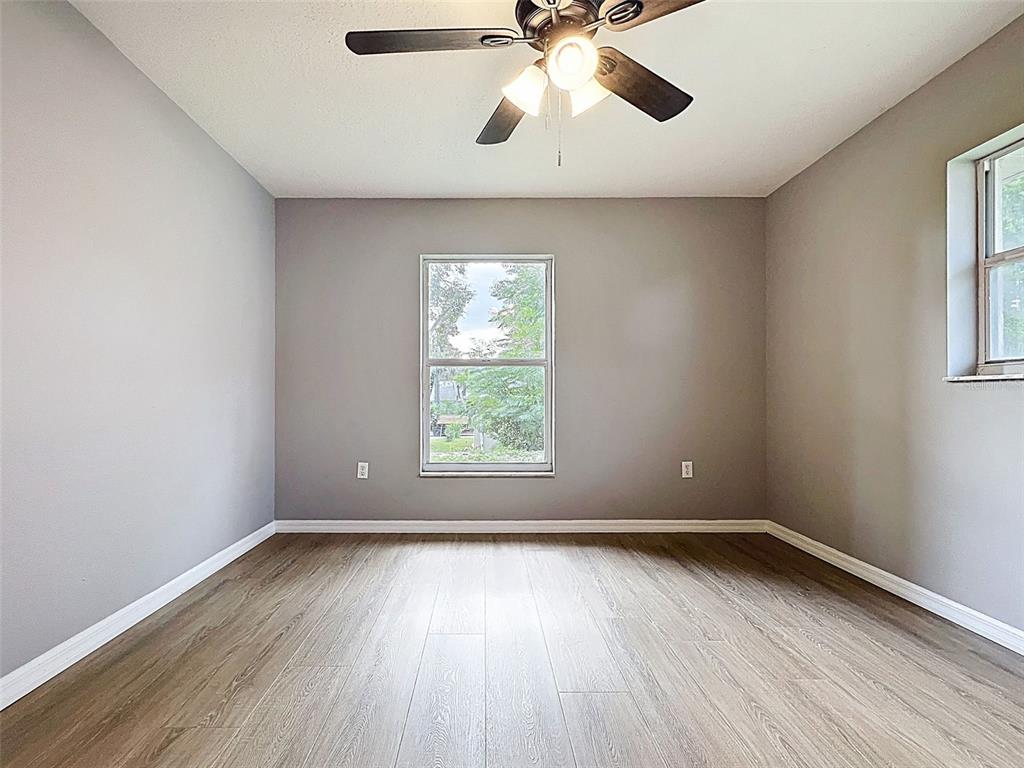 12214 Partridge Hill Row Hudson, FL 34667 - Photo 51 of 80 an empty room with wooden floor chandelier fan and windows