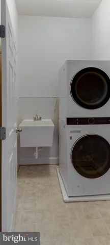 a bathroom with a sink and a washer dryer and white cabinets