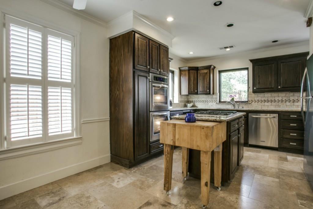 5419 Merrimac Avenue Dallas, TX 75206 - Photo 9 of 17 Kitchen featuring dark wood cabinetry, stainless steel appliances, stone tile flooring, granite countertops, and a subway tile backsplash