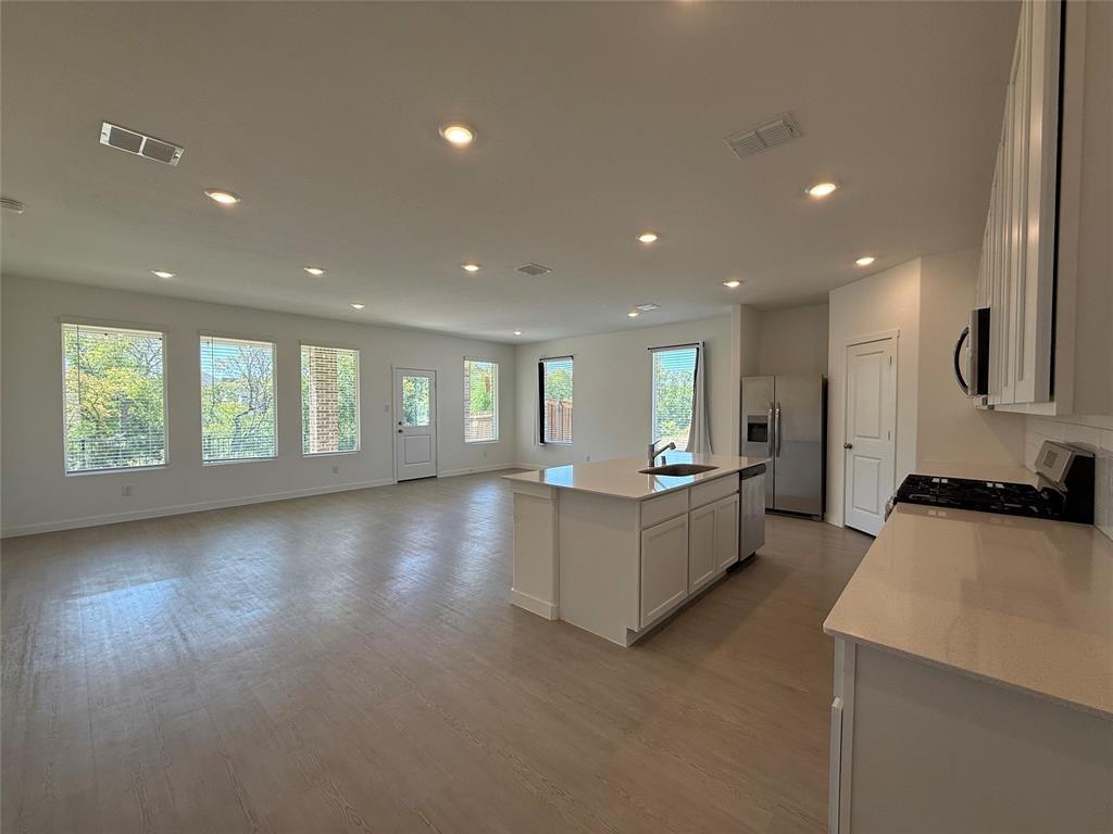 3025 Timber Rdg Drive Anna, TX 75409 - Photo 6 of 23 Open-concept kitchen and living area featuring wood-finish flooring, recessed lighting, and ample natural light from multiple windows