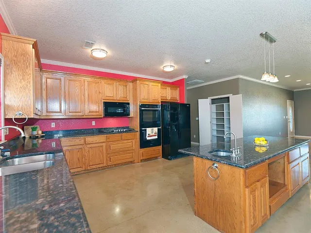 a kitchen with stainless steel appliances kitchen island granite countertop a stove a sink and a refrigerator