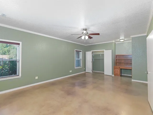 an empty room with chandelier fan and windows