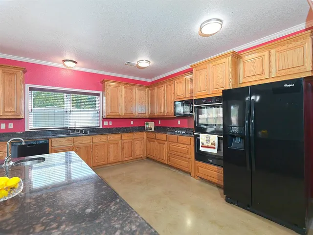 a kitchen with stainless steel appliances kitchen island granite countertop a refrigerator and a stove top oven