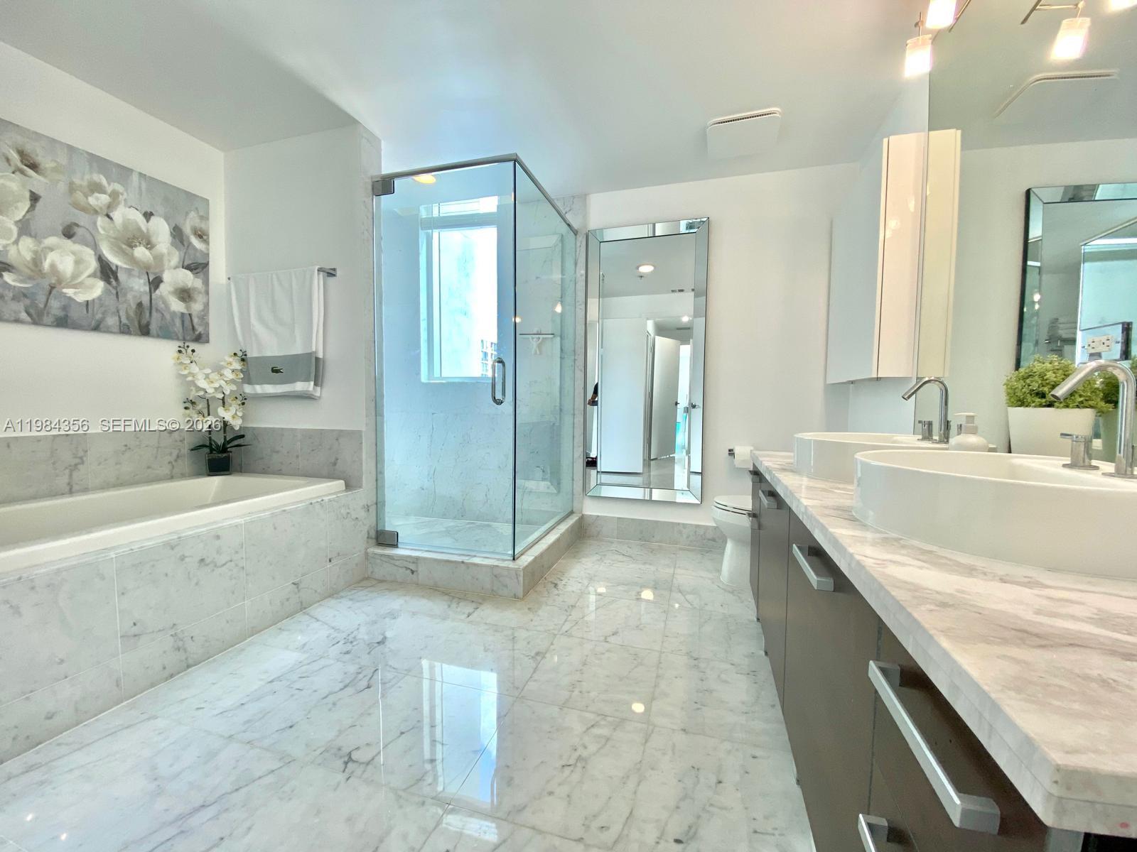 253 Northeast 2nd Street, Unit 2703 Miami, FL 33132 - Photo 15 of 33 a spacious bathroom with a granite countertop tub sink and mirror