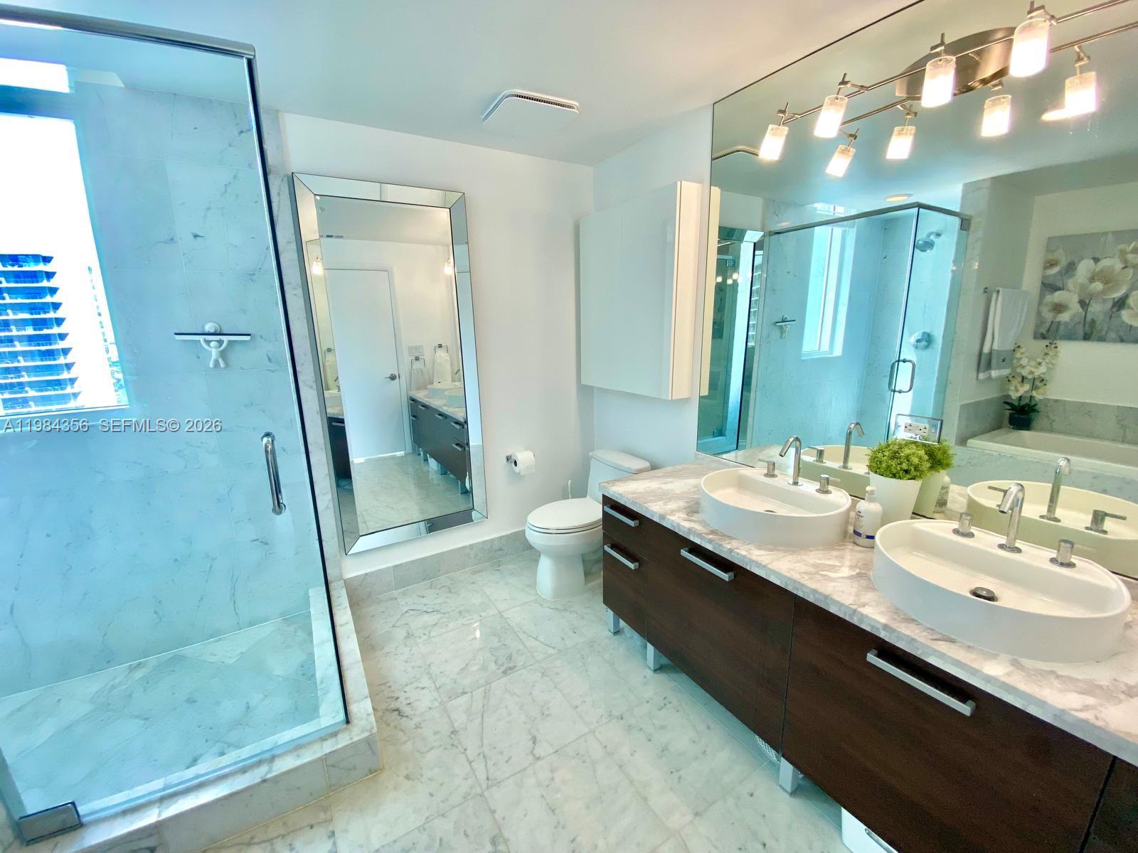 253 Northeast 2nd Street, Unit 2703 Miami, FL 33132 - Photo 16 of 33 a bathroom with a granite countertop sink a toilet and shower