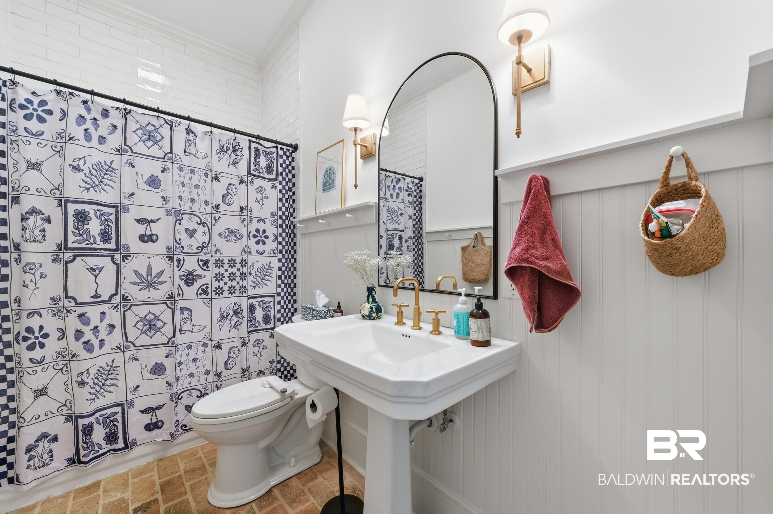 350 Charles Street Mobile, AL 36604 - Photo 28 of 52 Pedestal sink featuring brass-finish fixtures, a large arched mirror, and wainscoting paneling