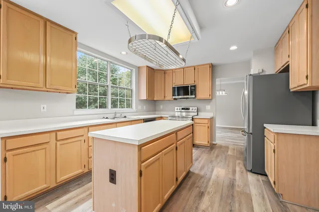 a large kitchen with stainless steel appliances granite countertop a large window a sink and a counter top space