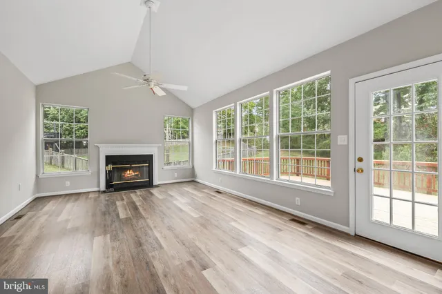 a view of an empty room with wooden floor fridge and a window