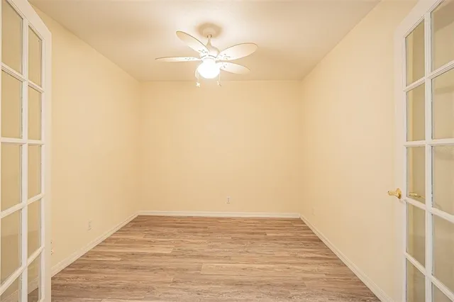 an empty room with wooden floor fan and windows