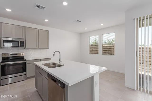 a kitchen with stainless steel appliances granite countertop a sink dishwasher a stove and a refrigerator with wooden floor