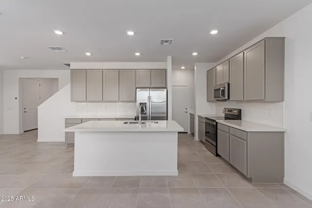 a kitchen with stainless steel appliances granite countertop a stove top oven a sink and a refrigerator