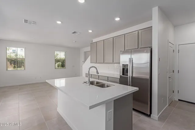 a kitchen with stainless steel appliances granite countertop a refrigerator a sink a stove and white cabinets