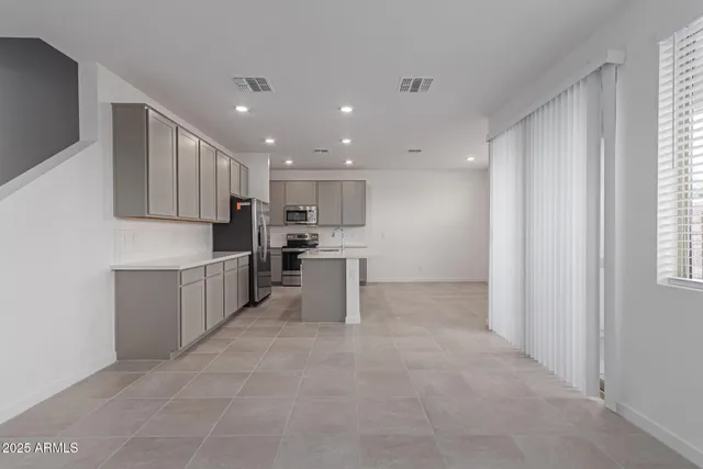 a kitchen with stainless steel appliances kitchen island sink refrigerator and cabinets