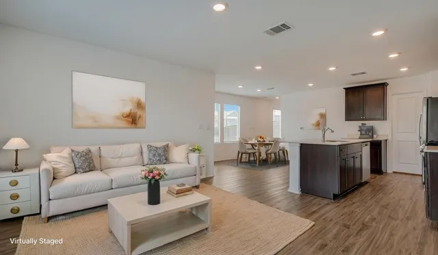 a living room with couches and kitchen view with wooden floor