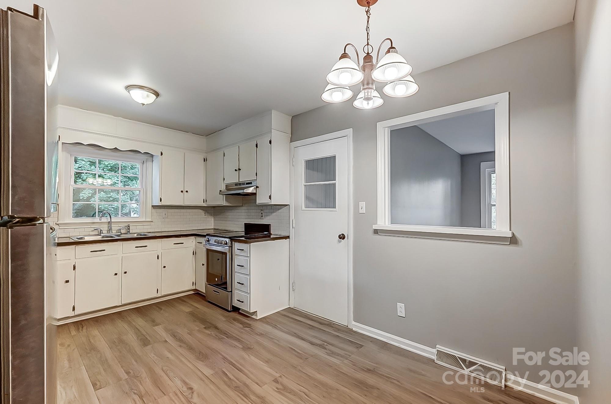 3218 Valley Grove Road Charlotte, NC 28227 - Photo 8 of 23 a kitchen with a refrigerator a sink dishwasher a stove and white cabinets with wooden floor
