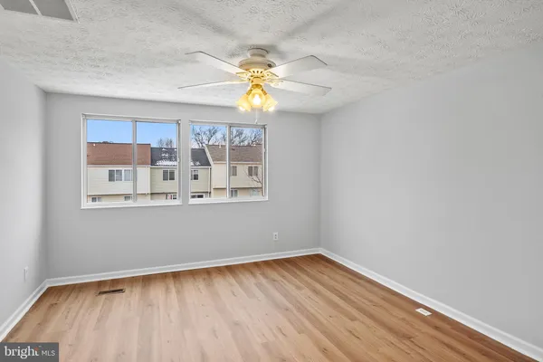 a view of empty room with wooden floor and fan