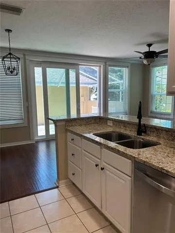 a kitchen with granite countertop a sink and a white wooden cabinets