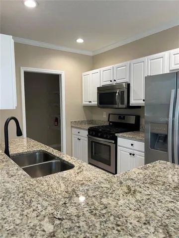 a kitchen with granite countertop a refrigerator stove and sink