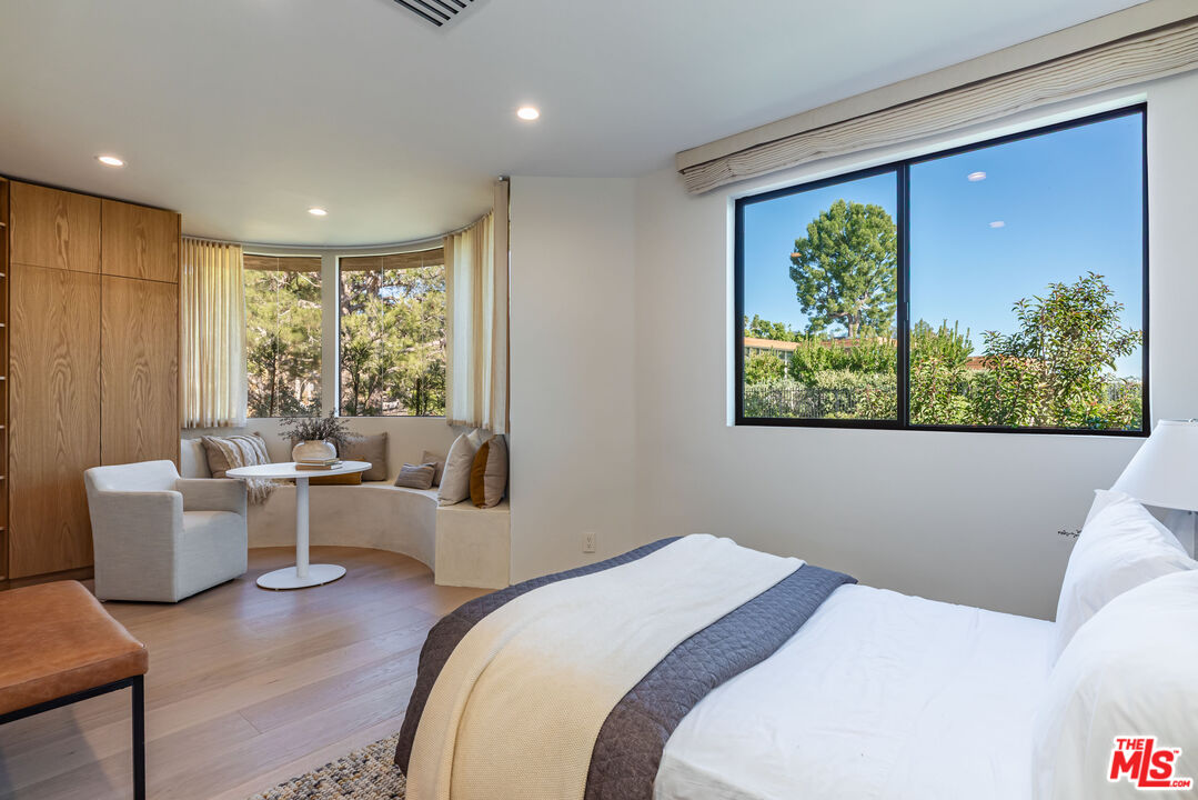 1705 Carla Ridge Beverly Hills, CA 90210 - Photo 24 of 39 a bedroom with a large window and a wooden floor