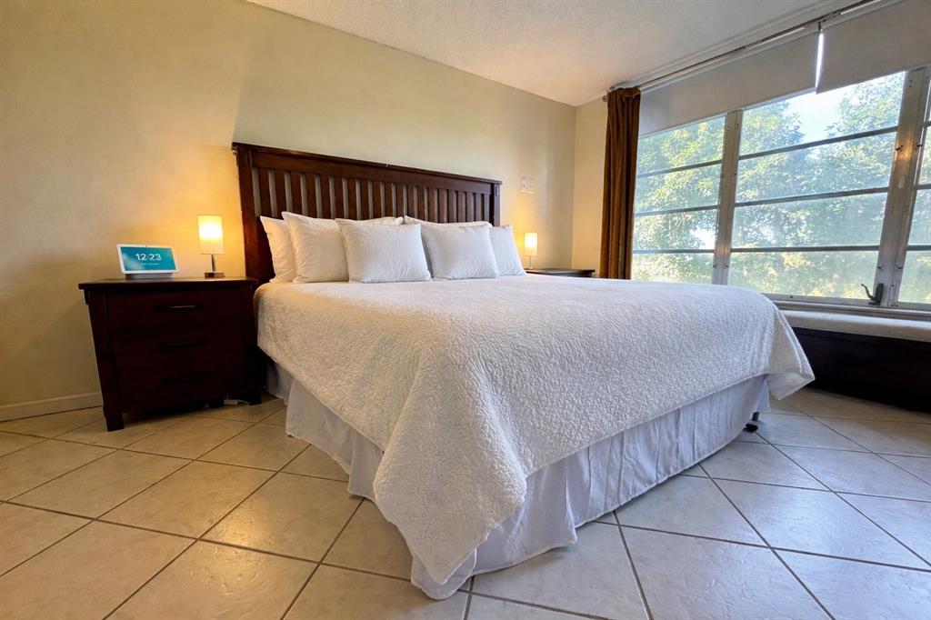 2601 South Course Drive, Unit 305 Pompano Beach, FL 33069 - Photo 12 of 20 a bed sitting in a bedroom next to a window