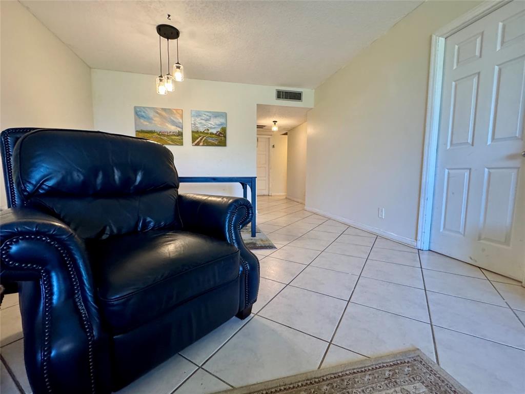 2601 South Course Drive, Unit 305 Pompano Beach, FL 33069 - Photo 17 of 20 a bedroom with a bed and a chandelier