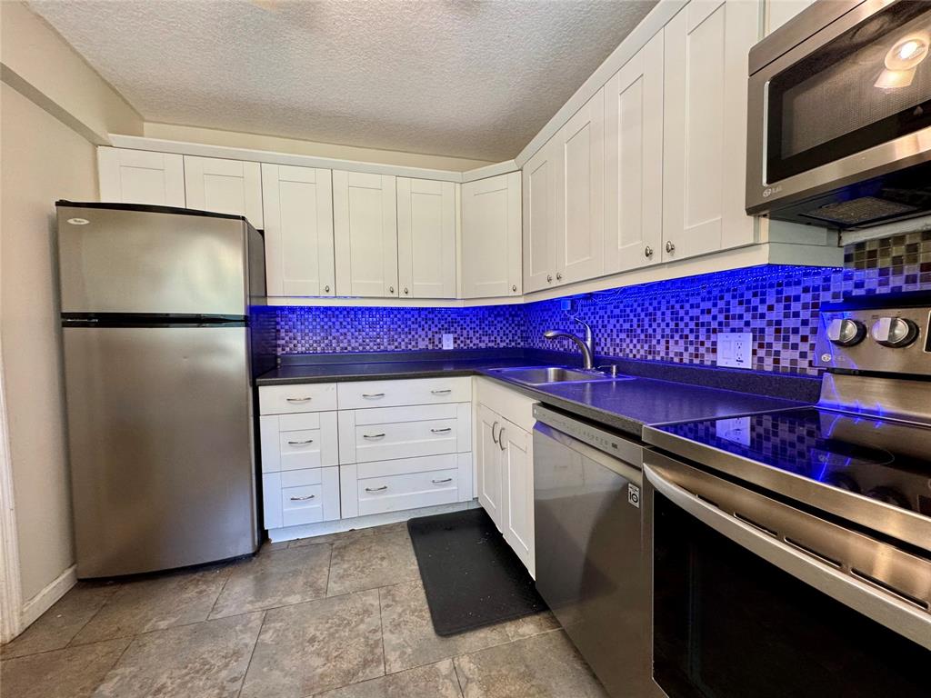 2601 South Course Drive, Unit 305 Pompano Beach, FL 33069 - Photo 18 of 20 a kitchen with stainless steel appliances a refrigerator sink and cabinets