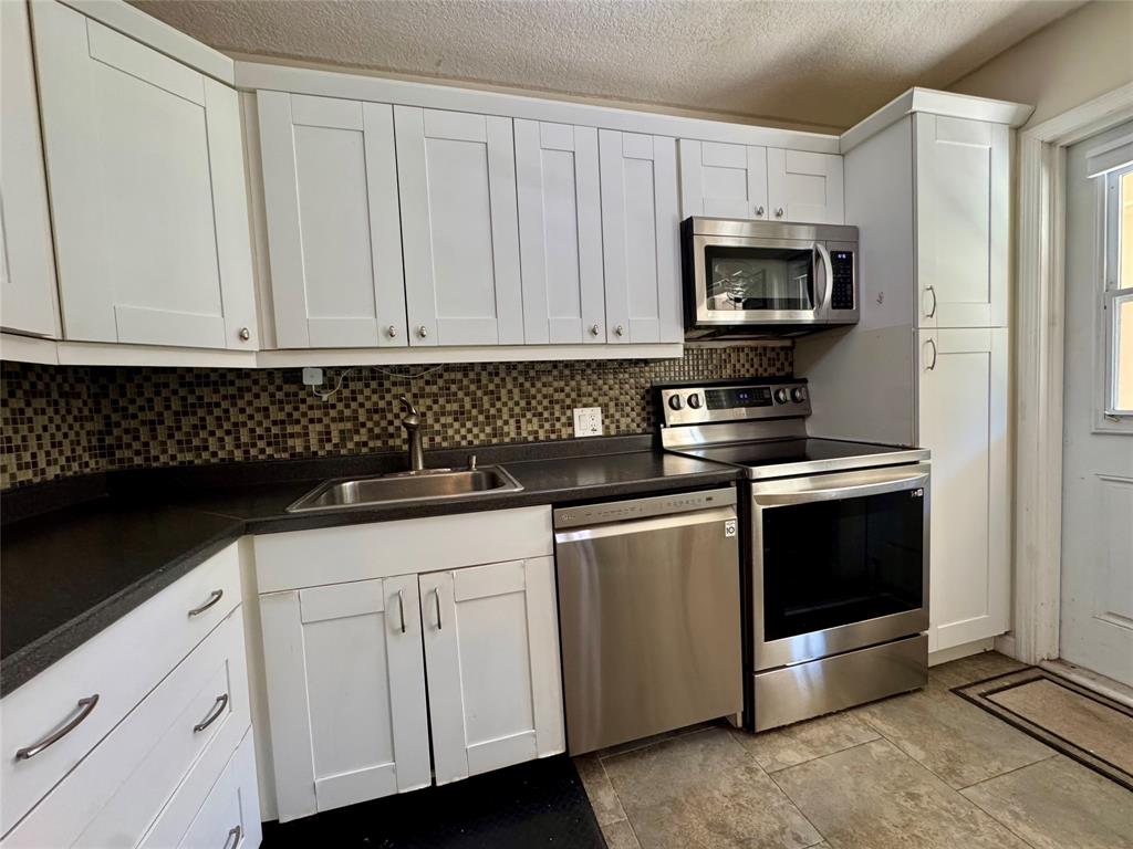 2601 South Course Drive, Unit 305 Pompano Beach, FL 33069 - Photo 2 of 20 a kitchen with white cabinets and black appliances