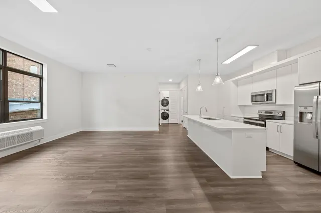 a large white kitchen with lots of counter space wooden floor and appliances
