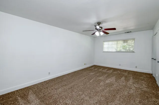 an empty room with windows and chandelier fan