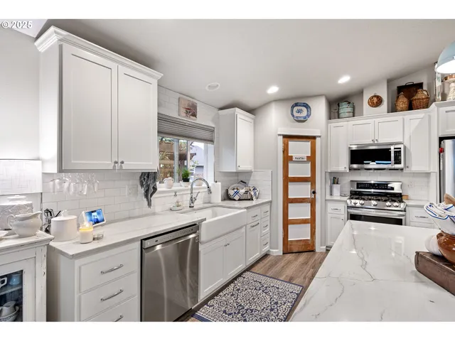 a kitchen with stainless steel appliances granite countertop a sink dishwasher stove and refrigerator with wooden cabinets