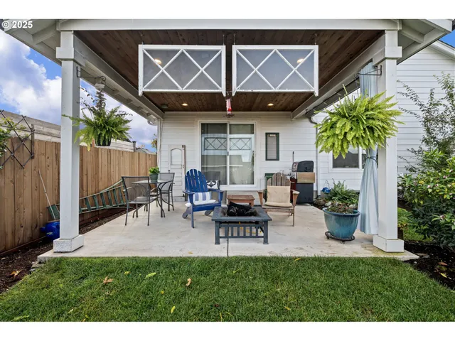 a view of a backyard with table and chairs potted plants and a wooden fence