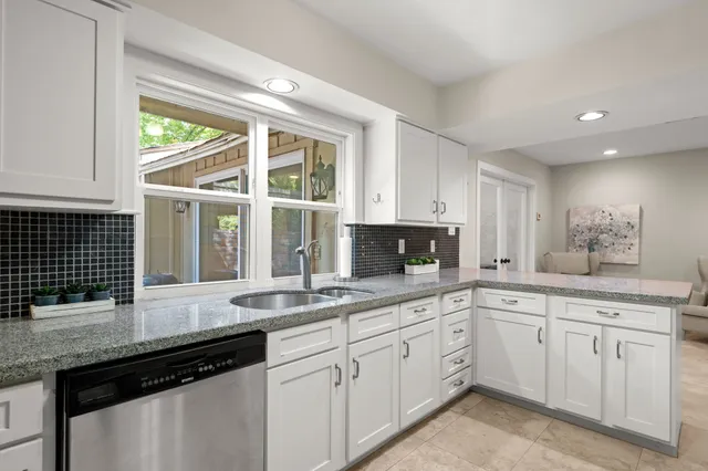 a kitchen with white cabinets and a window