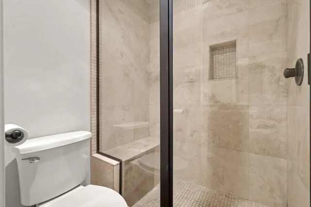 a white toilet sitting next to a shower