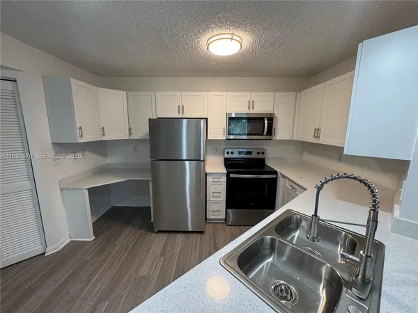 a kitchen with a refrigerator sink and wooden cabinets