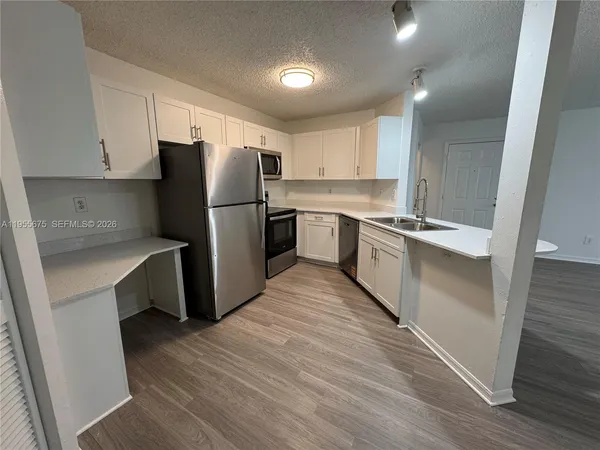 a kitchen with a refrigerator sink and wooden cabinets