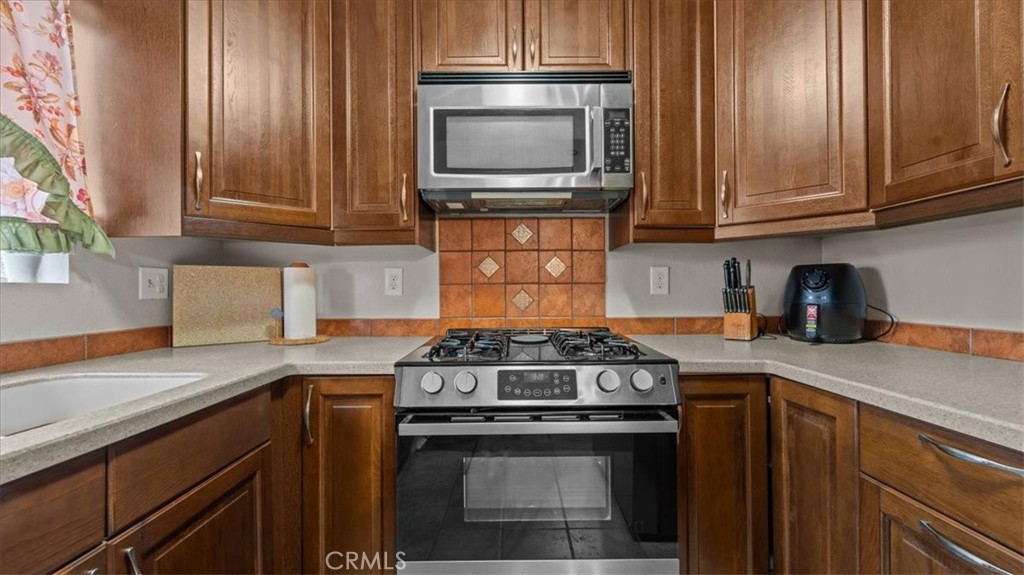 8425 Sunset Trail Place, Unit F Rancho Cucamonga, CA 91730 - Photo 9 of 28 a kitchen with granite countertop a stove top oven cabinetry a sink and dishwasher