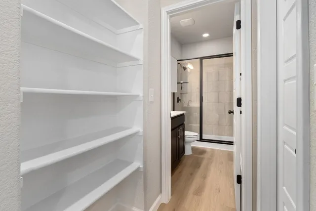 a view of a hallway with wooden floor and closet area