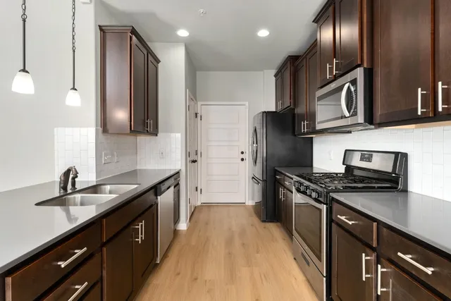 a kitchen with stainless steel appliances granite countertop a sink a stove and a refrigerator