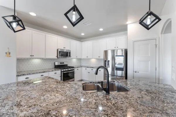 a kitchen with kitchen island granite countertop a stove top oven a sink a counter space and cabinets