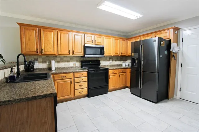 a kitchen with granite countertop a refrigerator stove top oven and sink