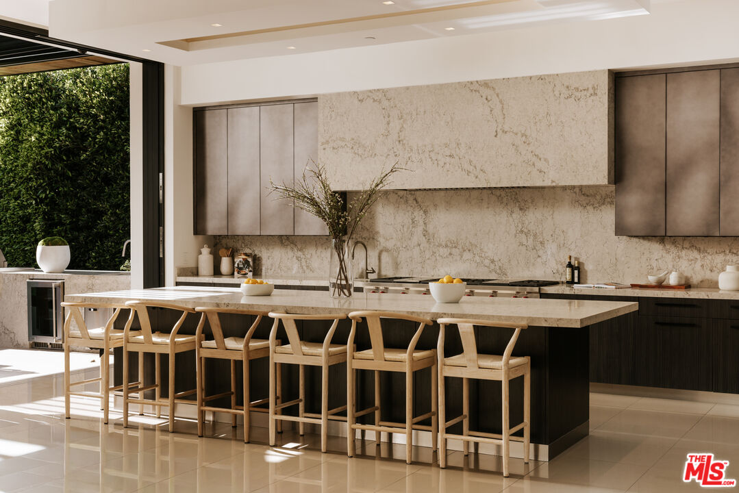 219 Homewood Road Los Angeles, CA 90049 - Photo 12 of 40 a large white kitchen with a kitchen island a stove a counter space and a sink