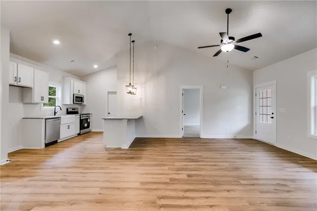 a view of a kitchen with kitchen island a sink stainless steel appliances and cabinets