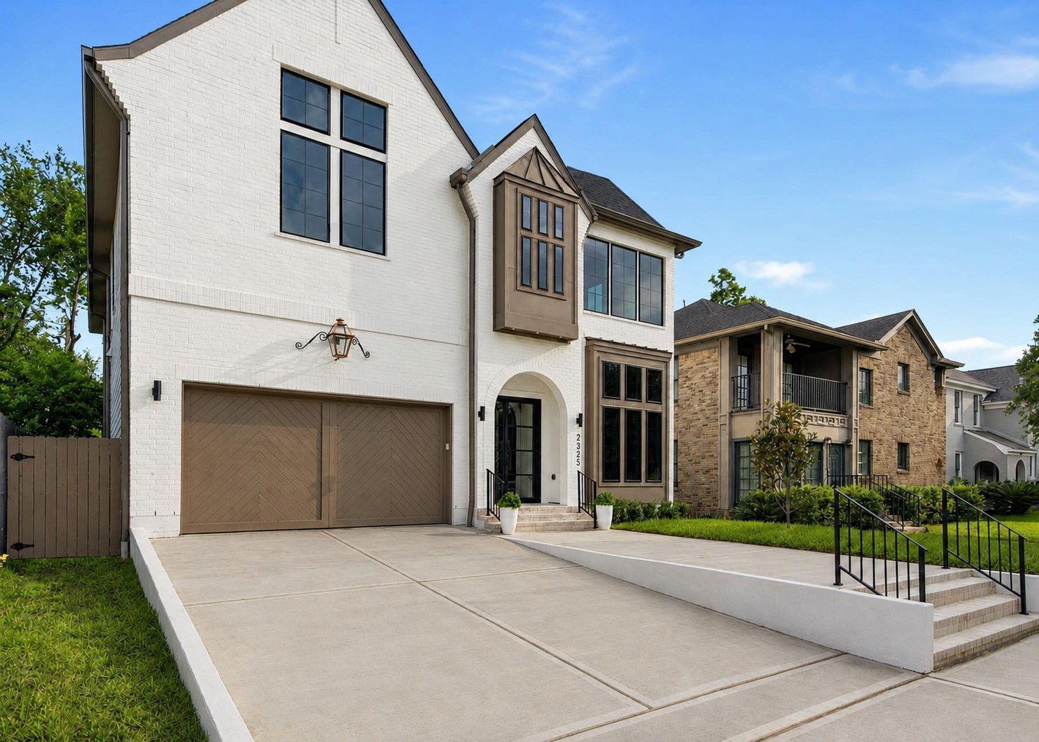 2325 Wroxton Road Houston, TX 77005 - Photo 3 of 34 Side profile of the front elevation displaying the stunning custom wood garage door, stunning tiered house profile, and gas lantern