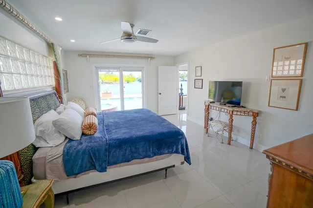 a bedroom with a bed mirror on dresser and a window