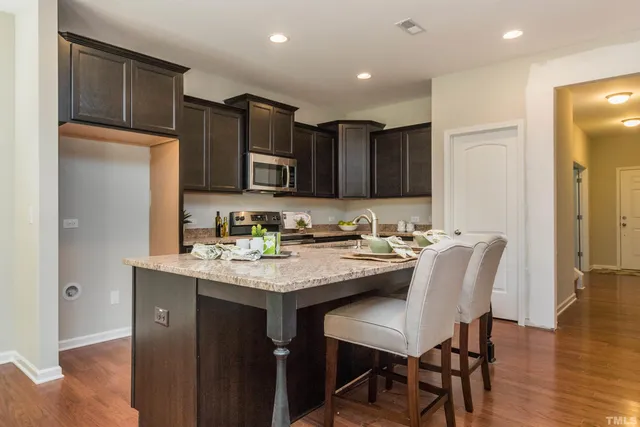 a view of kitchen with stainless steel appliances granite countertop a dining table and chairs in it