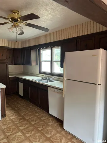 a kitchen with stainless steel appliances granite countertop a refrigerator a sink dishwasher a stove and a dining table with wooden floor