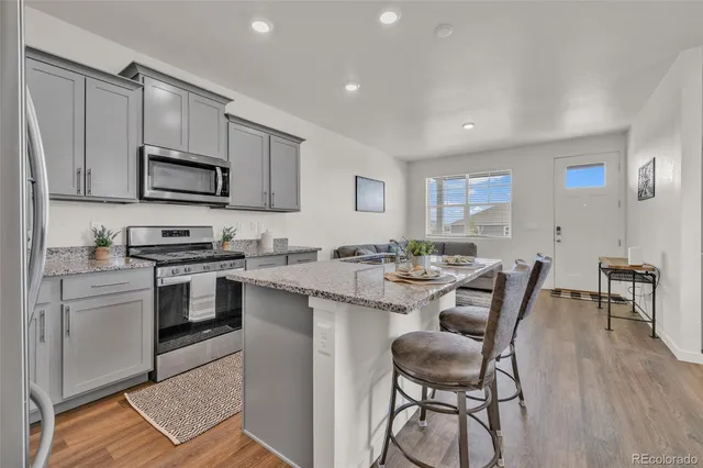 a kitchen with stainless steel appliances kitchen island granite countertop a stove a sink a microwave a dining table and chairs