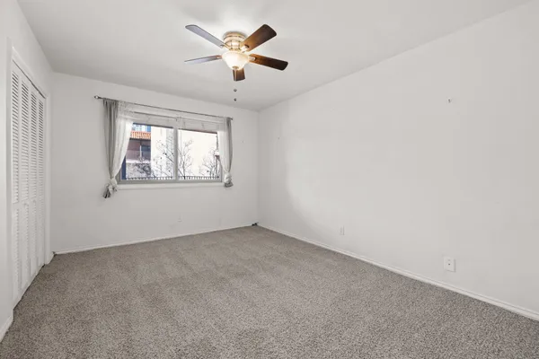 an empty room with a window and a fan