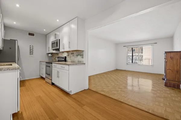 a kitchen with stainless steel appliances white cabinets a sink a stove a refrigerator and a microwave