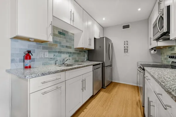 a kitchen with stainless steel appliances granite countertop a sink refrigerator and cabinets